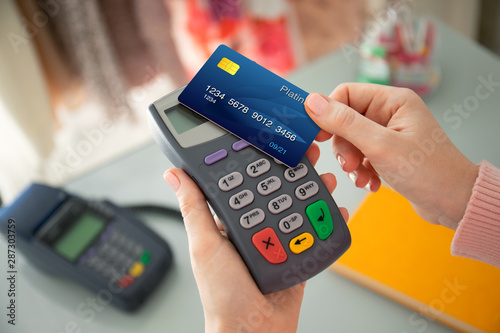 Woman hand holding plastic card and pay pass online terminal