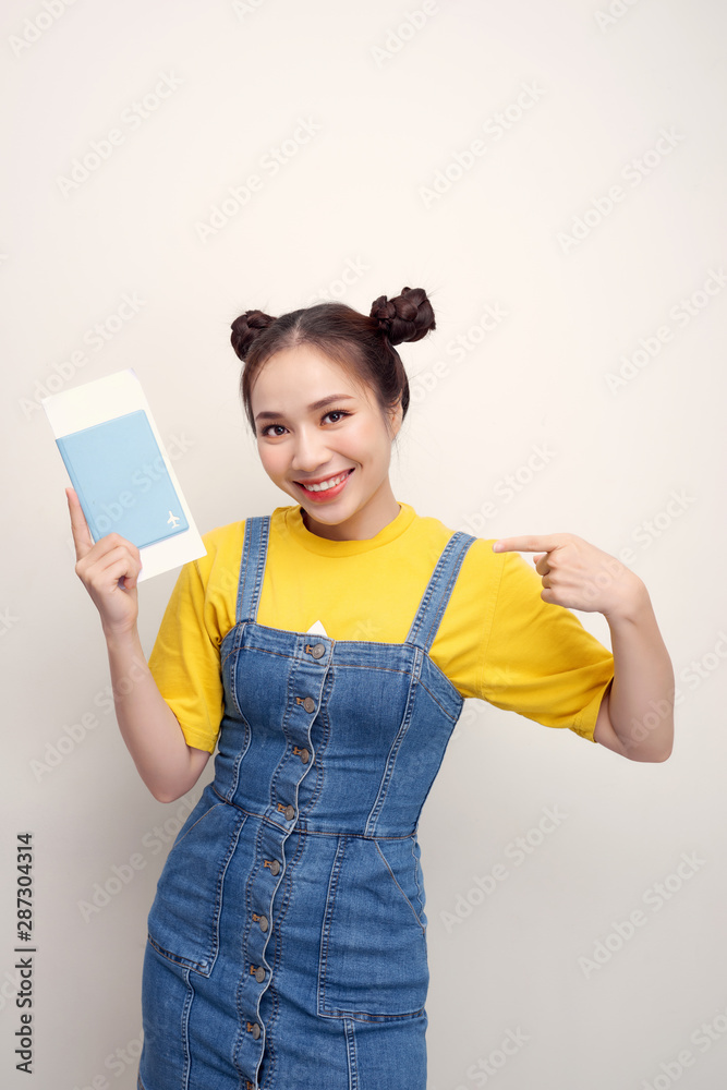 Attractive excited woman 20s smiling while holding passport with travel tickets isolated over white background Attractive excited woman 20s smiling while holding passport with travel tickets isolated over white background