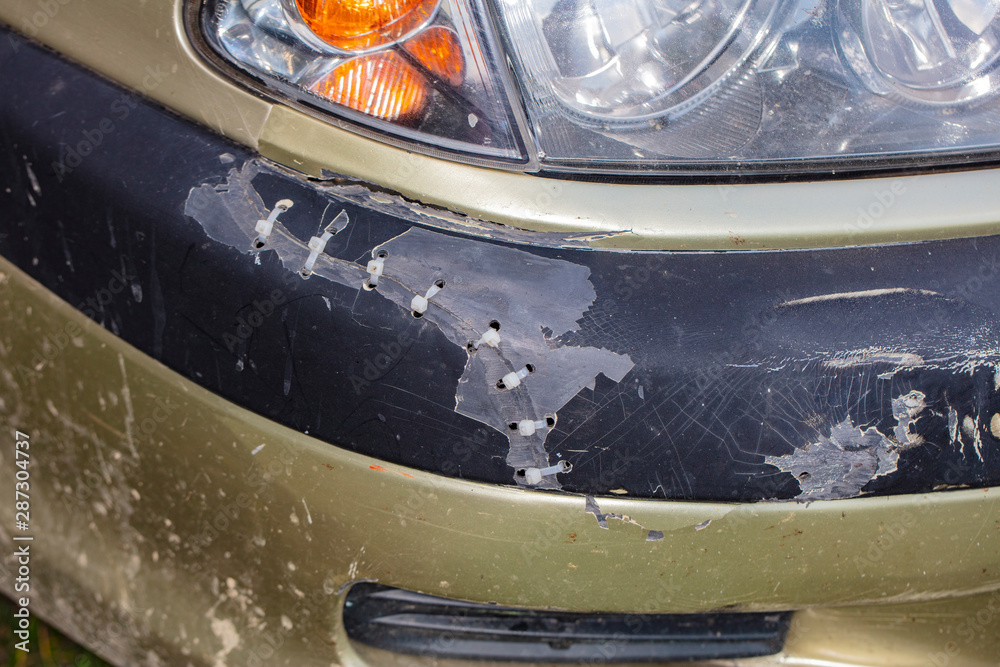 Obraz premium car bumper broken and connected with plastic threads