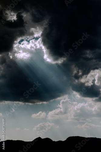 Rayos de luz atravesando el cielo negro, con montañas en el fondo