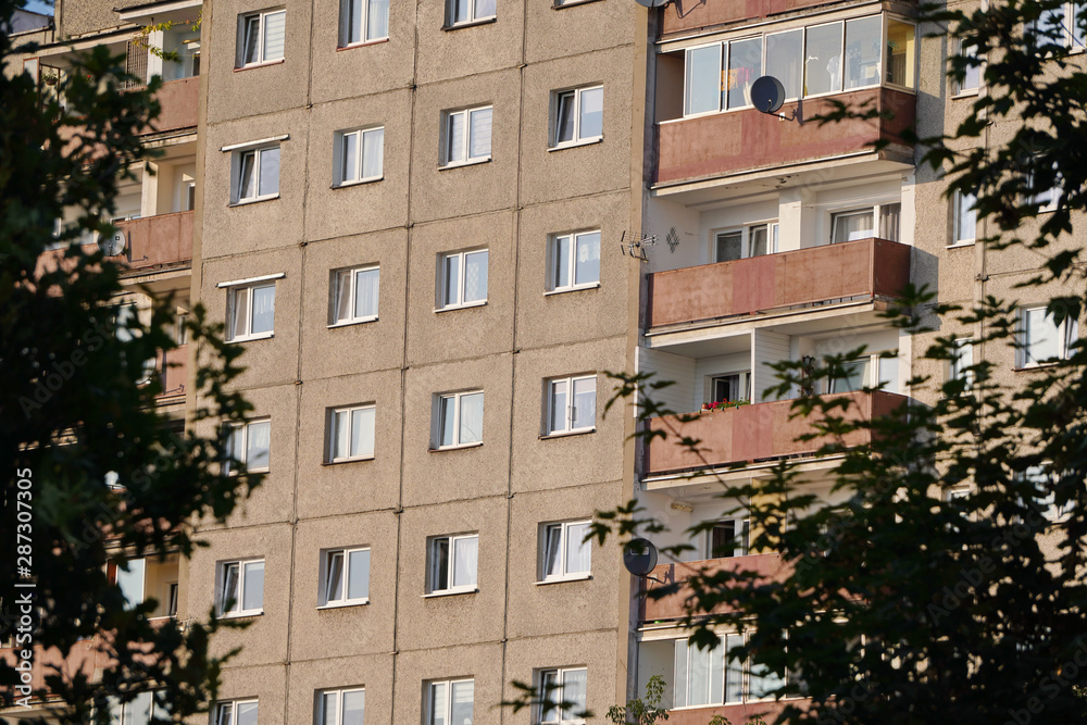 gray multi-storey panel house in a residential area of the big city among the trees, Windows and loggias, gray wall, the outside of the house, trees near the houses in the city gray multi-storey panel house in a residential area of the big city among the trees, Windows and loggias, gray wall, the outside of the house, trees near the houses in the city