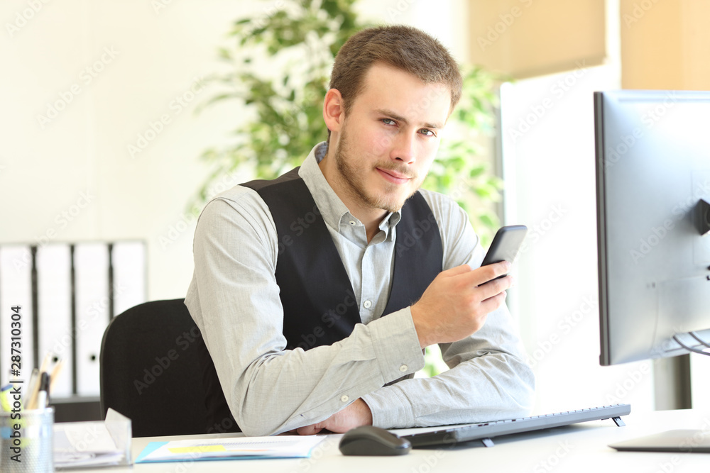 Serious executive holding phone looking at camera Serious executive holding phone looking at camera