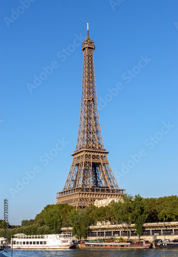 Paris, France: Eiffel tower in summer with Seine river and boats in foreground.