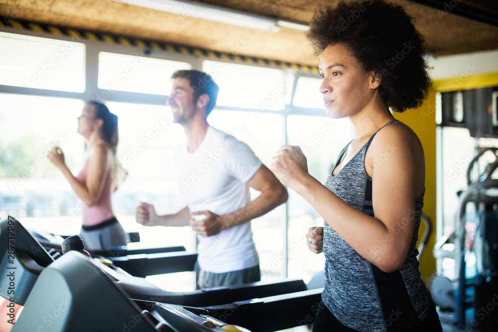 Young people running on a treadmill in health club. Young people running on a treadmill in health club.