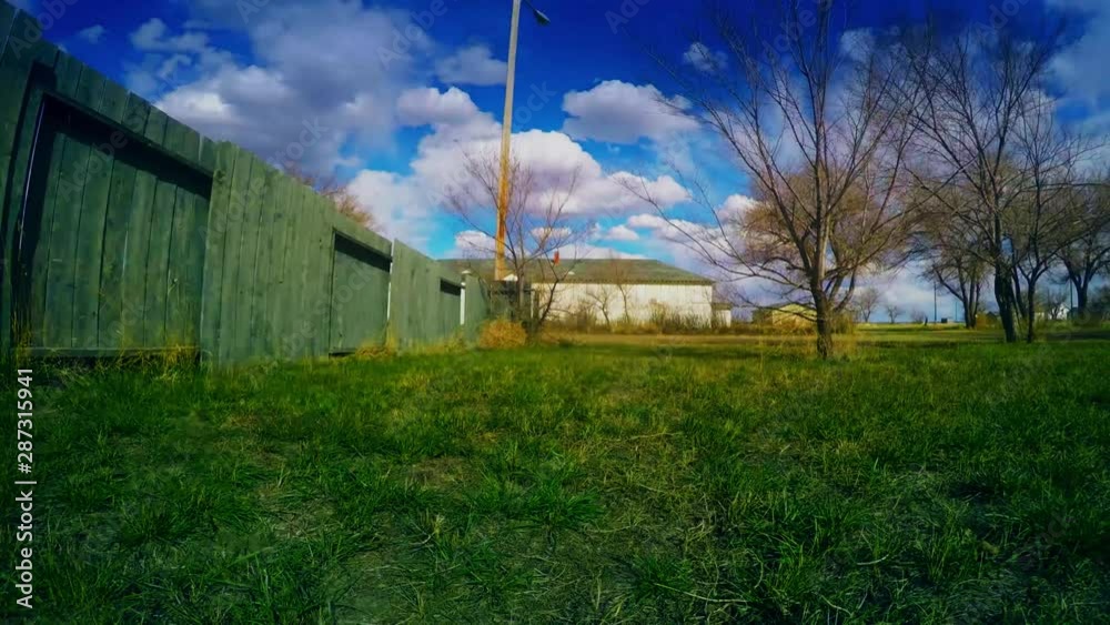 TIMELAPSE - clouds over a grass front lawn of a home across from a old building. TIMELAPSE - clouds over a grass front lawn of a home across from a old building.