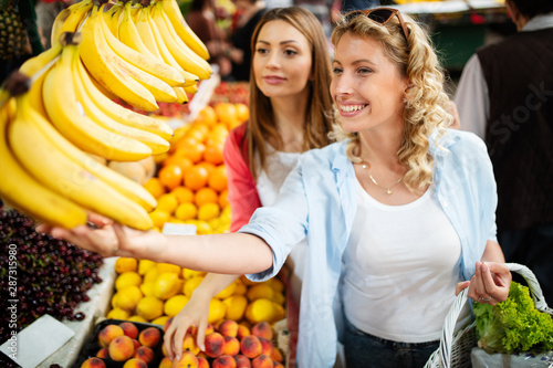 Young happy women shopping vegetables and fruits on the market