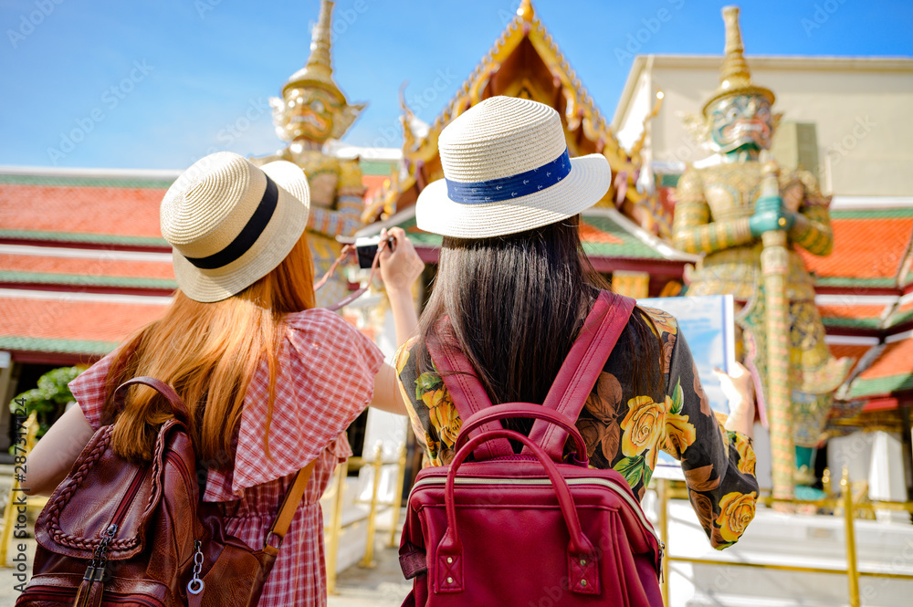 young tourist women enjoy trip taking picture on the palace temple in Bangkok of Thailand, Emerald Buddha Temple, Wat Phra Kaew, Bangkok Royal Palace popular tourist place