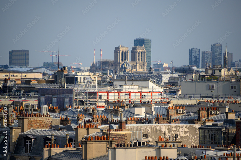 Notre Dame de Paris avec des toits et des cheminées en premier plan