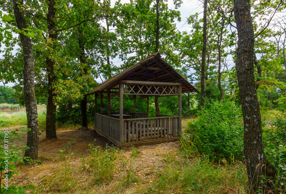 The wooden gazebo for picnic rest in the green forest The wooden gazebo for picnic rest in the green forest