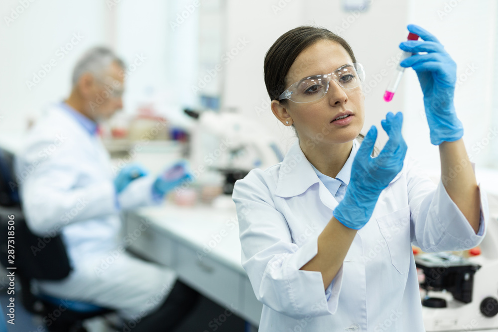 Serious young scientist doing chemical experiment in lab Serious young scientist doing chemical experiment in lab