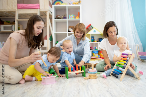 Mothers with their babies play with developmental toys in daycare centre