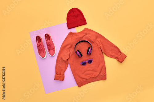 Hipster DJ trendy colorful autumn Outfit. Fall fashion Flat lay. Orange jumper, Stylish sneakers, headphones. Creative Woman Clothes Accessories layout. Fall Girl fashionable autumnal color.