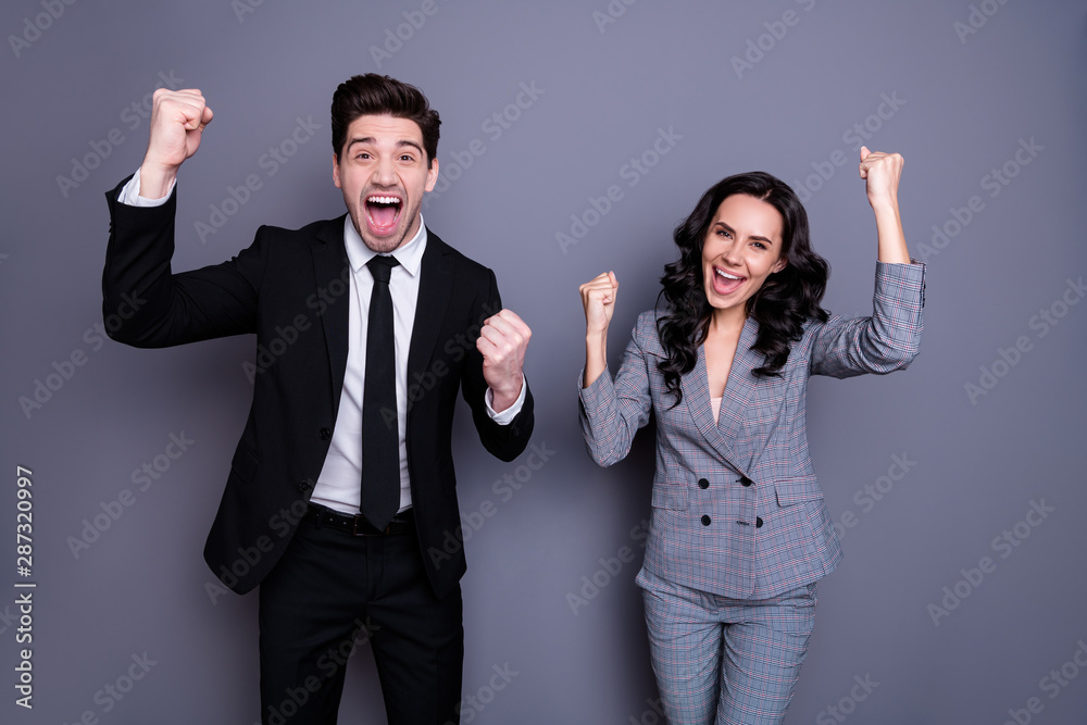 Portrait of ecstatic business people with wavy curly brunette hair raising fists screaming yeah wearing black blazer jacket trousers tuxedo pants isolated over gray background Portrait of ecstatic business people with wavy curly brunette hair raising fists screaming yeah wearing black blazer jacket trousers tuxedo pants isolated over gray background