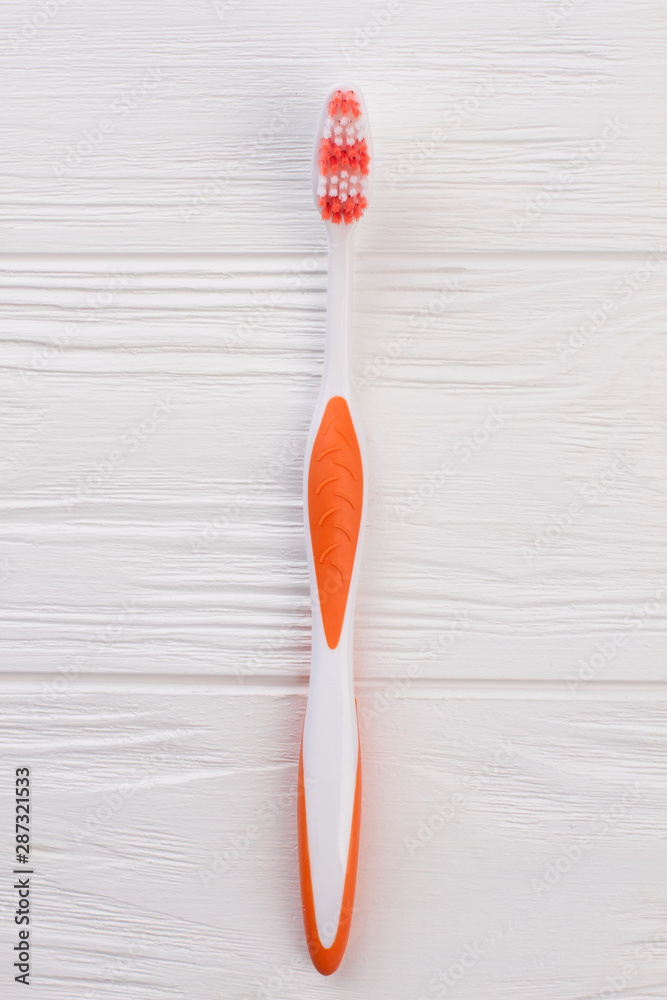 Orange tooth brush on white wooden background. Oral hygiene instrument. Top view, copy space. Orange tooth brush on white wooden background. Oral hygiene instrument. Top view, copy space.
