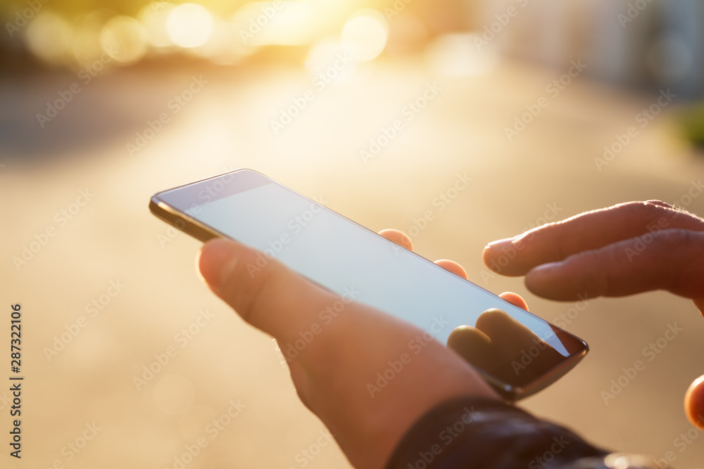 Man holding smart phone with blurred background. - obrazy, fototapety, plakaty 