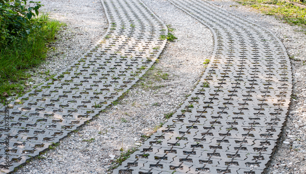 Fototapeta premium curved driveway of gravel and lawn grid stones