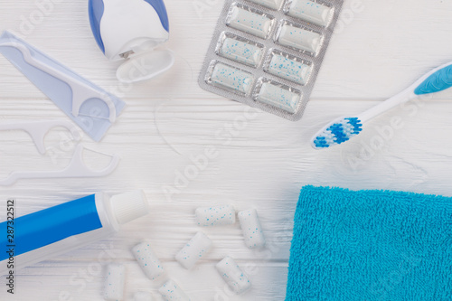 Toothpaste, toothbrush, dental floss and towel. Flat lay composition with toothbrush and oral hygiene products on wooden background. Dental health concept.