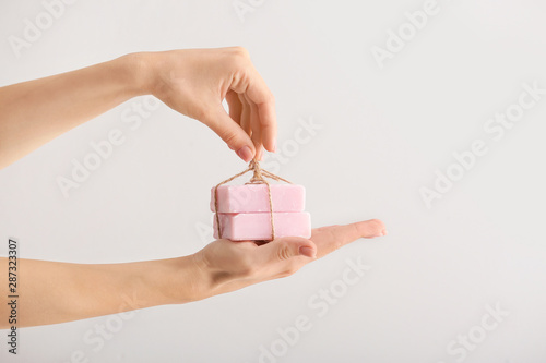 Female hands with soap bars on light background