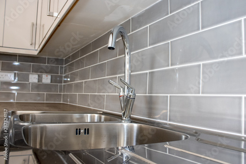 Typical kitchen sink taps with grey tiles,