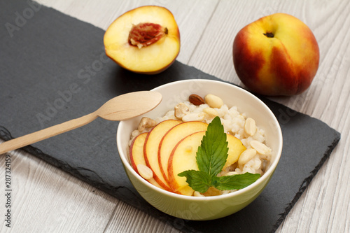 Sorghum salad with nuts and fresh peach on stone board.