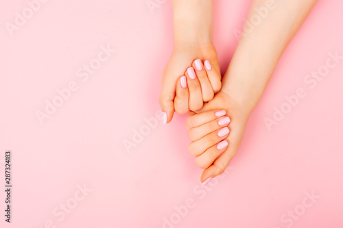 Manicure on two hands of a woman on a pink background with place for text. Flat lay