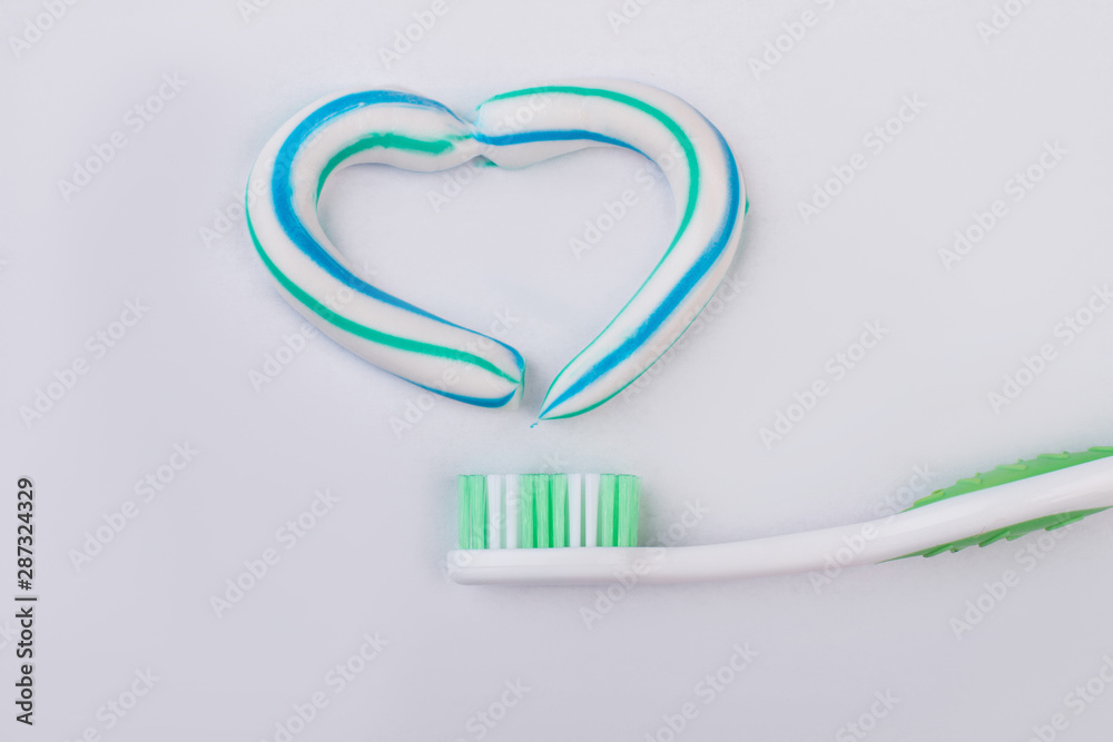 Toothbrush and heart made from a toothpaste. The heart symbol is made from a three-color toothpaste. Dental care concept. Toothbrush and heart made from a toothpaste. The heart symbol is made from a three-color toothpaste. Dental care concept.