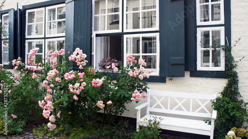 Beautiful cozy courtyard with white bench and flowers in the street of old town, Lubeck, Germany © Lunnaya