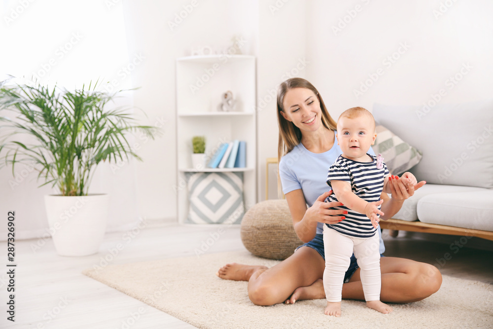 Mother teaching her little baby to walk at home