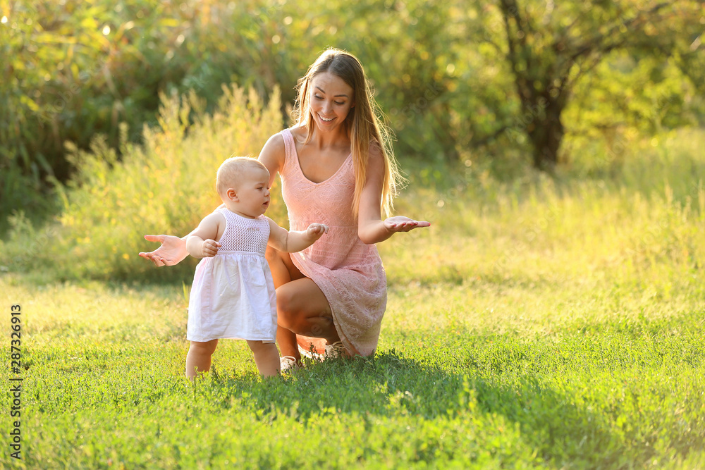 Mother teaching her little baby to walk outdoors Mother teaching her little baby to walk outdoors