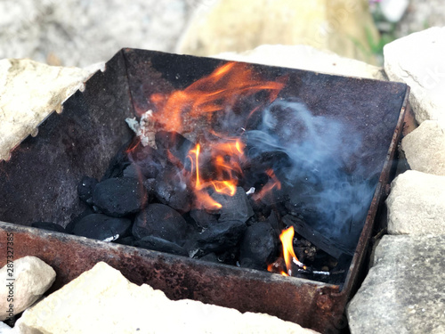 Fire burning in grill across carbon pieces. Cooking outside