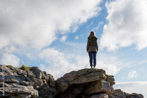 A girl stands high on stones. Success, happiness, freedom. Ocean and clouds. Beautiful nature landscape in Norway. Amazing scenic outdoors view in North. Travel, adventure, lifestyle. Lofoten Islands