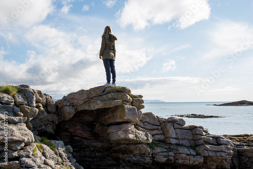 A girl stands high on stones. Success  happiness  freedom. Ocean and clouds. Beautiful nature landscape in Norway. Amazing scenic outdoors view in North. Travel  adventure  lifestyle. Lofoten Islands
