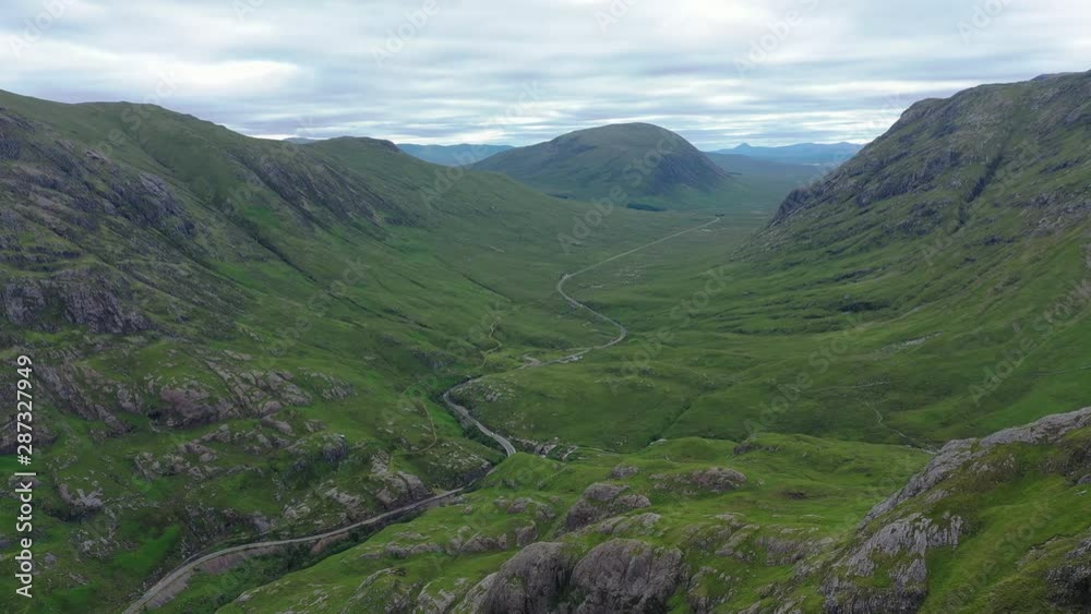 Aerial view of picturesque landscape of Glen Coe, scenic lush green valley surrounded by rocky hills of Highlands of Scotland - panorama of Scotland from above, United Kingdom, Great Britain, Europe Aerial view of picturesque landscape of Glen Coe, scenic lush green valley surrounded by rocky hills of Highlands of Scotland - panorama of Scotland from above, United Kingdom, Great Britain, Europe