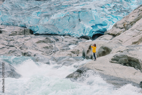 A girl stands on the background of the Nygardsbreen glacier and the glacial river in Norway.Adventure Lifestyle concept vacations outdoor Nigardsbreen glacier,Jostedalsbreen National Park