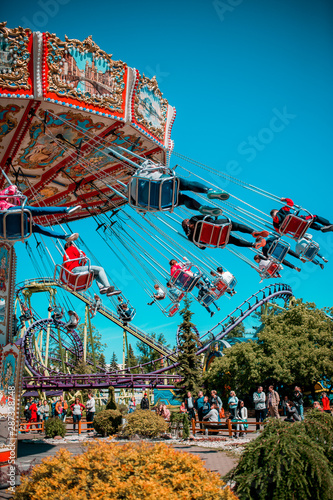 Colorful carrousel with kids on there. Chain swing carrousel in amusement park.