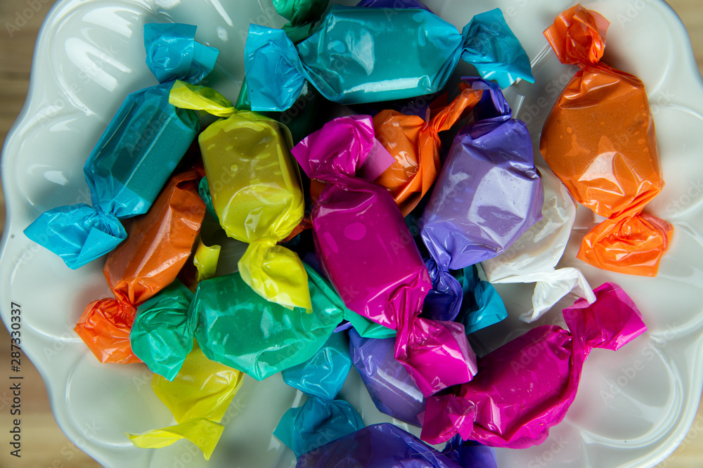 Top view beautiful colorful wrapped candies on white dish. Top view beautiful colorful wrapped candies on white dish.
