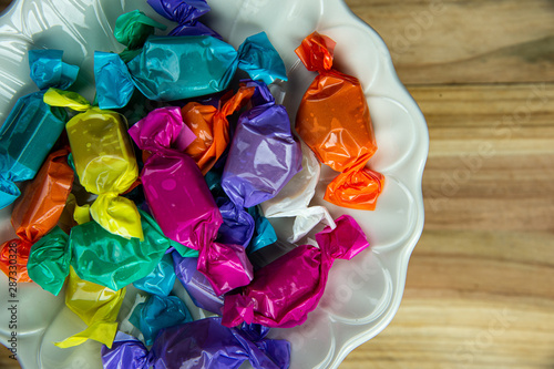 Obraz na płótnie Top view beautiful colorful wrapped candies on white dish.