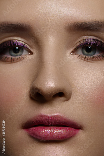 A close-up portrait of beauty with beautiful fashionable morning make-up, black snares on the eyes and extremely long eyelashes. pink lipstick on the lips. Cosmetology and spa facial skin care