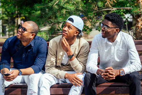 a group of three fashionable well-dressed cool African American guys students communicating on the street
