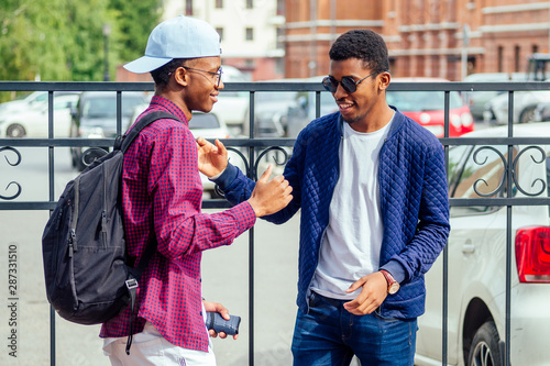 two stylish young friends hugging long-awaited meeting in street parking photo