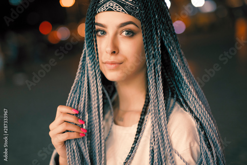 Portrait of young unconventional woman with blue pigtails in the night city
