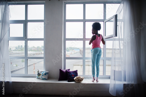 Young african american woman in pink singlet against window. Perfect morning.