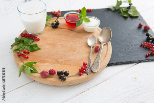 Free place for a dish or a plate. Berries, milk, yogurt on a cutting board on a wooden table. Place for cereal and healthy breakfast