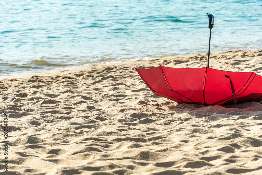 Red umbrella on sand on golden beach, forgotten by tourists. Background of azure sea, ocean. Red umbrella on sand on golden beach, forgotten by tourists. Background of azure sea, ocean.