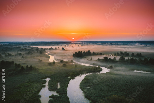 Aerial View Green Meadow And River Landscape In Misty Foggy Morning. Top View Of Beautiful European Nature From High Attitude In Summer Season. Drone View. Bird s Eye View