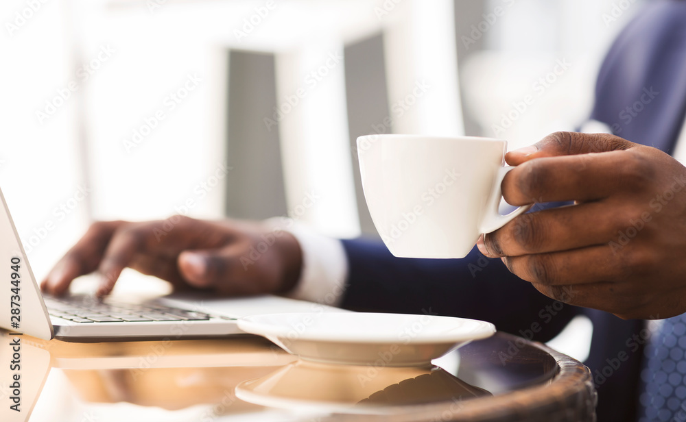 Afro Businessman Browsing On Laptop Drinking Coffee In Cafe, Closeup Afro Businessman Browsing On Laptop Drinking Coffee In Cafe, Closeup