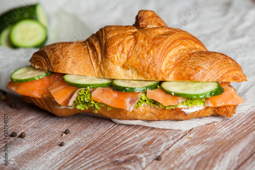 Croissant sandwiches served on wooden board. Croissants with egg, melted cheese, parsley, chicken ham, smoked salmon