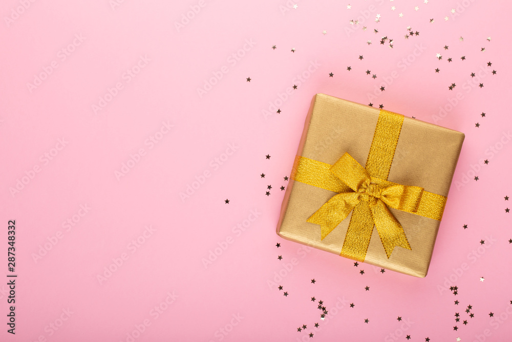 Gift or present box and stars confetti on color table top view. Flat lay composition for birthday, mother day or wedding.