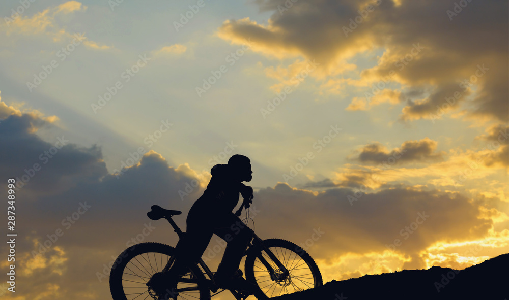 Obraz premium Cyclist in shorts and jersey on a modern carbon hardtail bike with an air suspension fork rides off-road on the orange-red hills at sunset evening in summer 