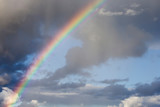 Rainbow and white clouds in blue sky after rain. Nature, travel concept, copy space